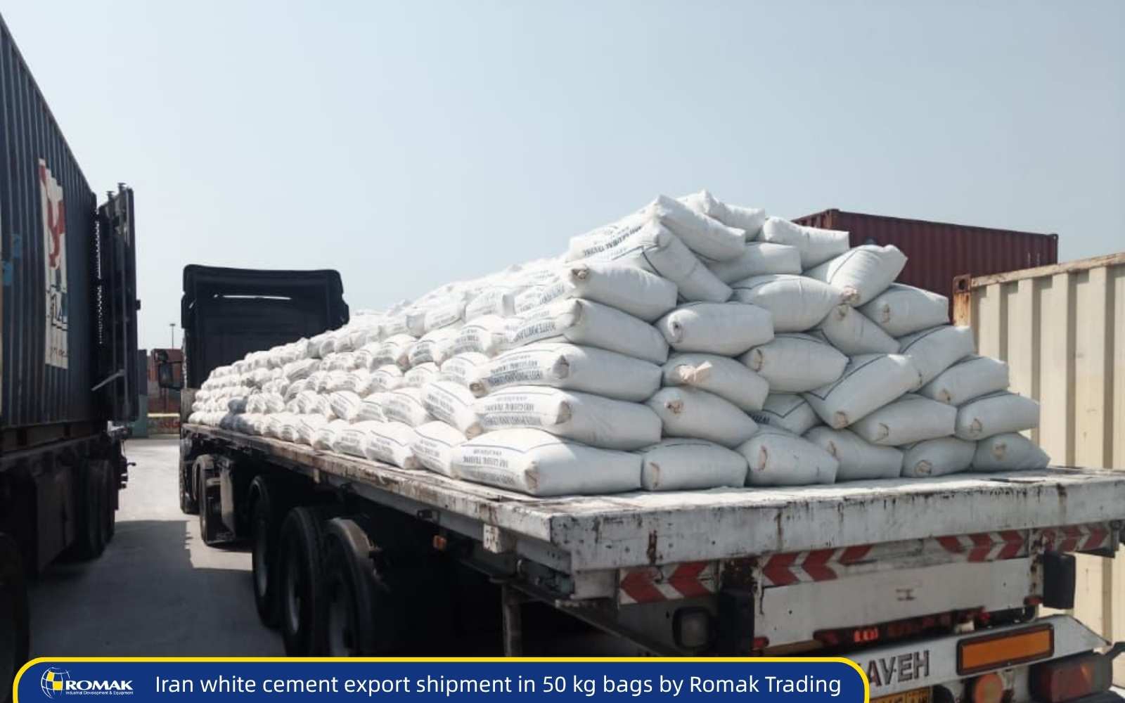 Flatbed truck loaded with stacked 50 kg white cement bags ready for export from Romak Trading